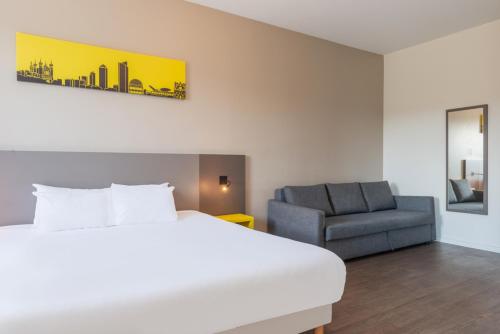a hotel room with a bed and a chair at Westlodge Dardilly Lyon Nord in Dardilly