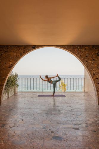 a woman doing a yoga pose in an archway at Green Coast Hotel MGallery Collection in Vlorë