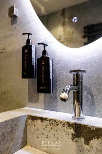 a bathroom sink with two soap dispensers and a mirror at Meliora in Nea Artaki