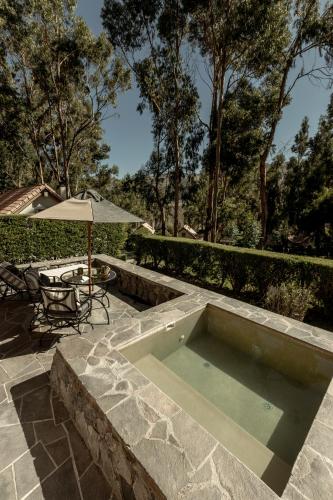 a swimming pool with a table and an umbrella at Las Casitas, A Belmond Hotel, Colca Canyon in Yanque