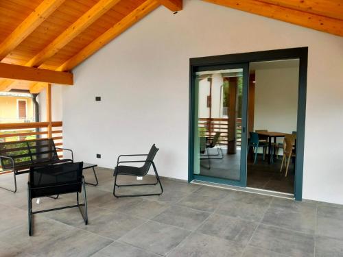 a patio with chairs and a table and a glass door at Casa Cuor di Castagno in Roncegno