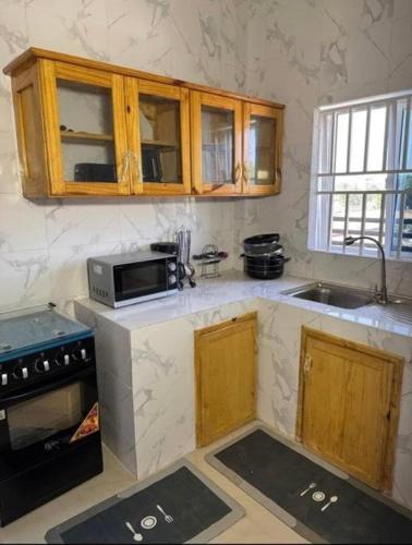 a kitchen with wooden cabinets and a microwave at Apartments in Sukuta high way in Serekunda