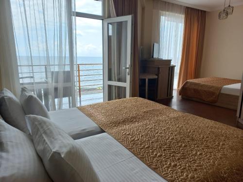a hotel room with a bed and a view of the ocean at Hotel Lazuri in Kvariati