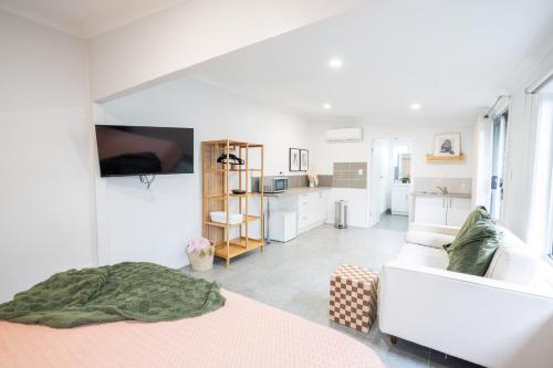 Una habitación blanca con una cama y un sofá. en Pink Muse, 3 Mins To Ettalong Beach, en Ettalong Beach
