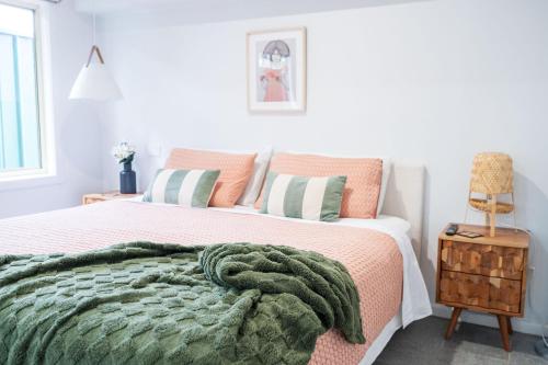 Un dormitorio con una cama con una manta verde. en Pink Muse, 3 Mins To Ettalong Beach, en Ettalong Beach