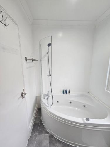 a white bathroom with a tub and a shower at Mirandas Place in Gillingham
