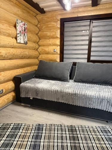 a bed in a room with a log wall at Гірські Будиночки in Synevyrsʼka Polyana