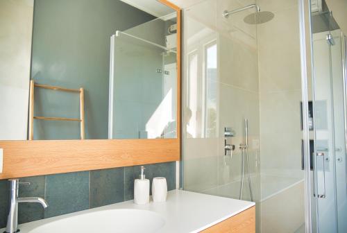 a bathroom with a sink and a shower with a mirror at Wake of the lake - bright waterfront apartment in Lecco
