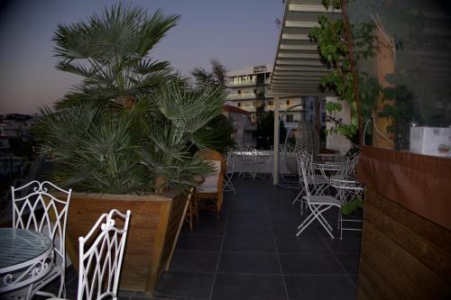 a patio with white chairs and tables and plants at Ilio Boutique Hotel in Ksamil