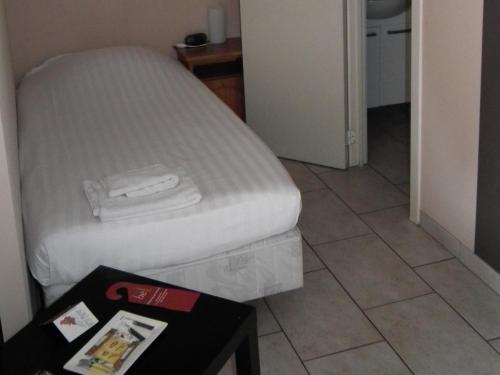 a bed in a small room with a table and a bed at Condo Gardens Brussels in Brussels