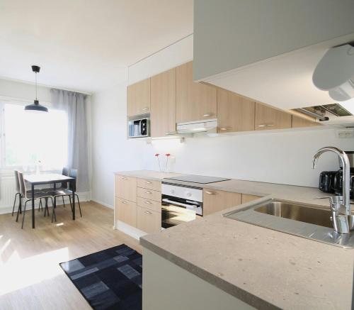 a white kitchen with a sink and a table at Spacious Apartment for 6 in Kouvola