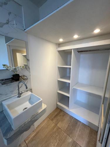 a white bathroom with a sink and shelves at Suite Sol Maragogi in São José da Coroa Grande