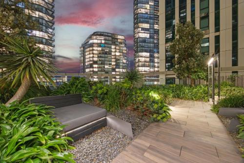 a garden with a bench and some tall buildings at Docklands Harbour & City Views Pool, Free Onsite Parking , Yoga & Gym in Melbourne