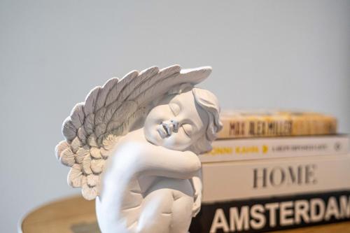 a white angel statue sitting on top of a stack of books at Docklands Harbour & City Views Pool, Free Onsite Parking , Yoga & Gym in Melbourne
