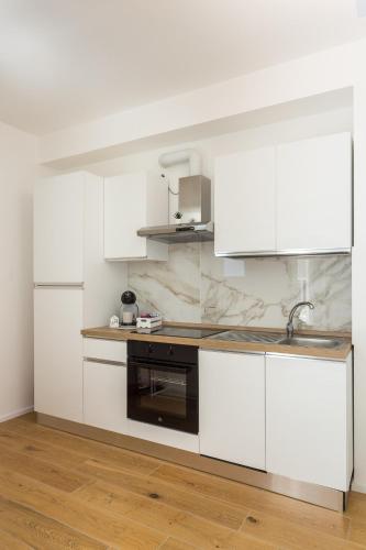a white kitchen with white cabinets and a sink at Dimora Caprera - Appartamenti in Falconara Marittima