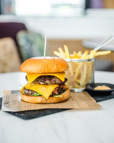 a cheeseburger on a bun with cheese and french fries at YOTEL Porto in Porto
