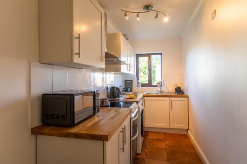a kitchen with white cabinets and a microwave oven at K Suites - Tollgate Court in Colchester