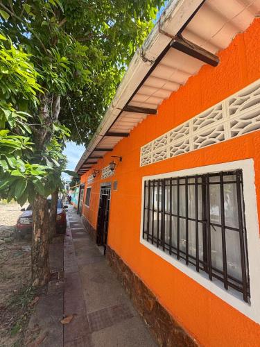 an orange building with a tree next to it at Casa sol en el jardin - piscina y relajacion total in Carmen de Apicalá