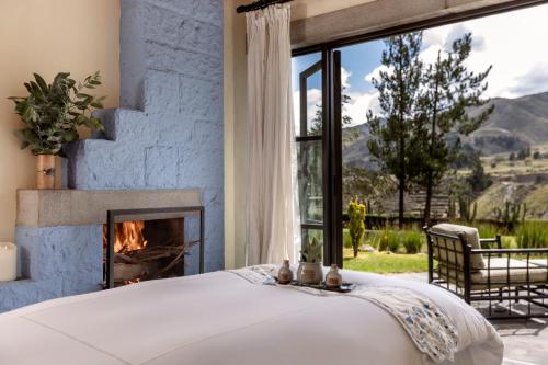 a bed in a bedroom with a fireplace at Las Casitas, A Belmond Hotel, Colca Canyon in Yanque