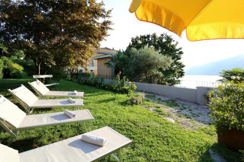 a row of white lounge chairs on a lawn with an umbrella at Casa Elli Serbelloni 12 in Bellagio