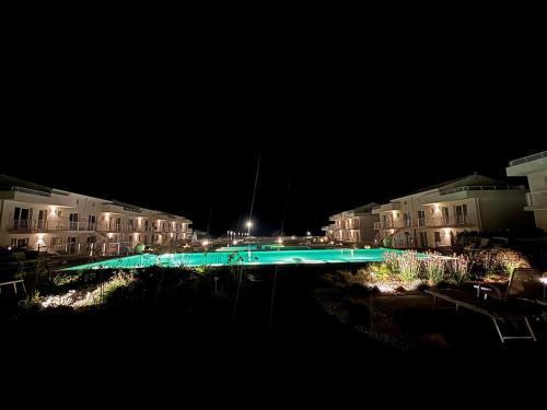 a lit up swimming pool at night with buildings at Flamingo Apartment in Pachino