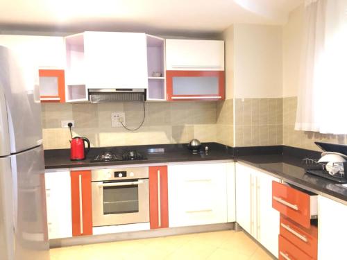 a kitchen with white cabinets and a stainless steel refrigerator at Enkombe Place in Kampala