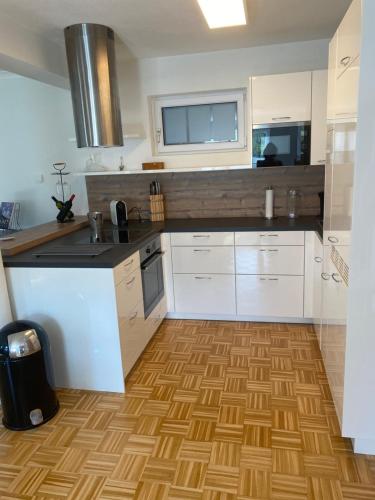a kitchen with white cabinets and a wooden floor at Schönes Apartment mit Terrasse, mitten im Grünen Stattegg in Stattegg