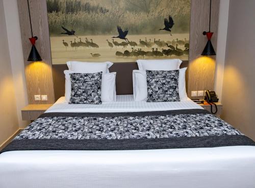 a bedroom with a white bed with pillows and a painting at Azalaï Hôtel Ouagadougou in Ouagadougou