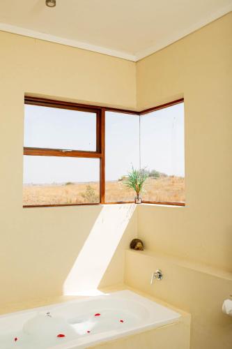 a bath tub in a bathroom with a window at Vetho Farmhouse Dullstroom in Dullstroom