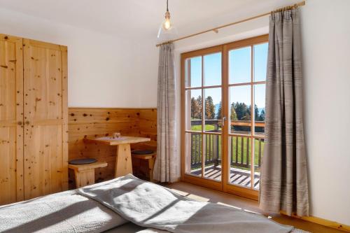 une chambre avec un lit et une grande fenêtre dans l'établissement Oberfahrerhof Jenesien, à Meltina