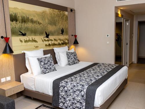 a bedroom with a large bed with a painting on the wall at Azalaï Hôtel Ouagadougou in Ouagadougou