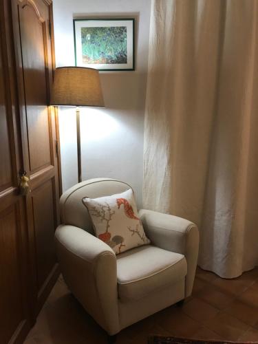 a chair with a pillow and a lamp in a room at Le jardin secret de Laura in Lorgues