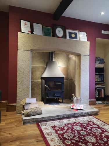a fireplace with a stove in a living room at Green Grove Country House in Malham