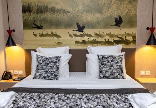 a bedroom with a bed with a painting on the wall at Azalaï Hôtel Ouagadougou in Ouagadougou