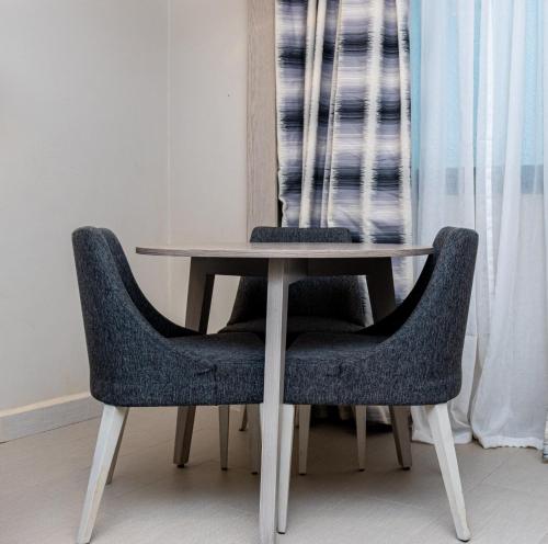 a wooden table with two chairs and a table and a window at Azalaï Hôtel Ouagadougou in Ouagadougou