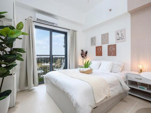 ein weißes Schlafzimmer mit einem großen Bett und einem Fenster in der Unterkunft Château Nude in Cebu City