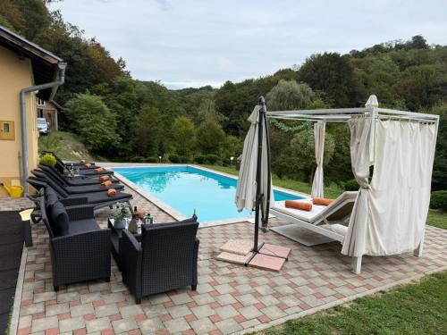 a swimming pool with chairs and an umbrella at VILA LASOVIC + POOL + JACUZZI + SAUNA in Tuhelj