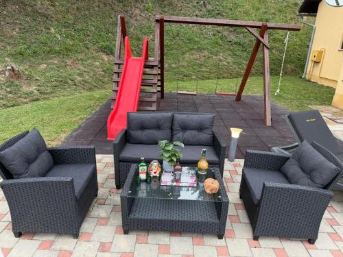 a patio with two couches and a red slide at VILA LASOVIC + POOL + JACUZZI + SAUNA in Tuhelj
