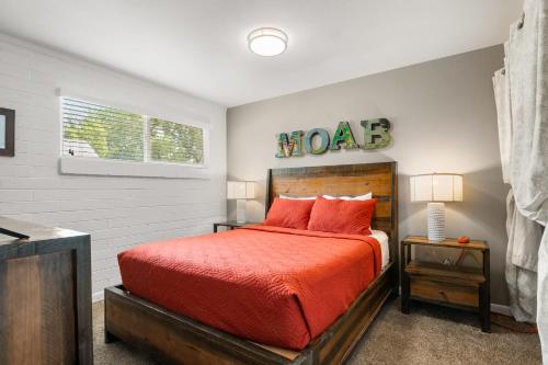 a bedroom with a bed with a red comforter and a window at Downtown Cozy Home Base - Purple Sage 3 in Moab