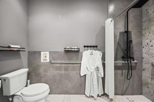 a bathroom with a shower with a white robe at La Buena Vida Inn in San Juan