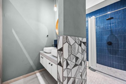 a bathroom with a sink and a shower with blue tiles at La Buena Vida Inn in San Juan