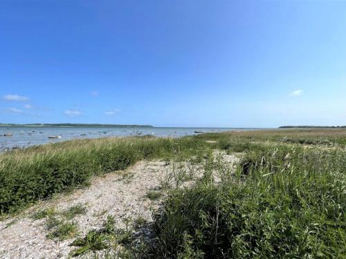 Una playa con césped y el agua con barcos en ella. en Holiday Home Esme - 225m to the inlet by Interhome, en Holbæk