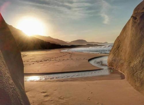 a view of a beach with the sun setting at Chalé Mar e Montanha - Próximo praia do cepilho in Paraty