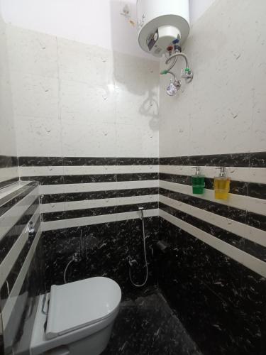 a bathroom with a toilet and a black and white striped wall at Kashi V Homestay in Varanasi
