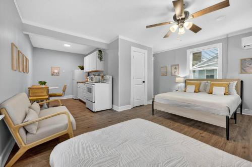 a bedroom with two beds and a chair and a kitchen at Unit 19 Tiny Haven Unwind in Pensacola in Pensacola