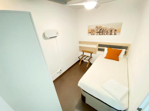 a small bedroom with a bed and a chair at Lumen Triplex by Oshun LOFTS & MIDSTAY in Madrid