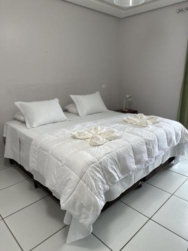 a large white bed with white sheets and pillows at Hotel Borari in Alter do Chao