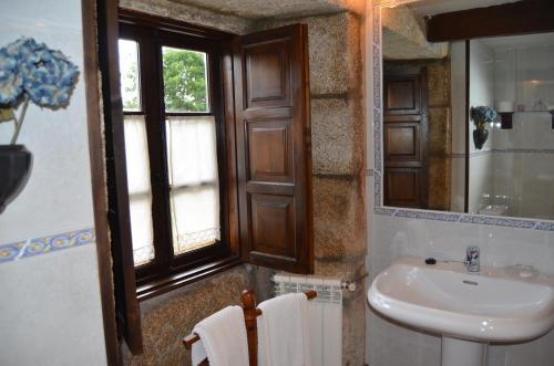 a bathroom with a sink and a toilet and a window at Casa de Martiño in Friol