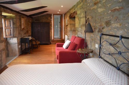 a bedroom with a bed and a red couch at Casa de Martiño in Friol