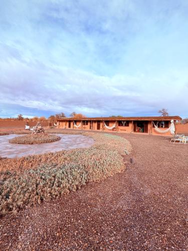 a building in the middle of a field with a building at MAKTVB - EcoLodge San Pedro de Atacama in San Pedro de Atacama